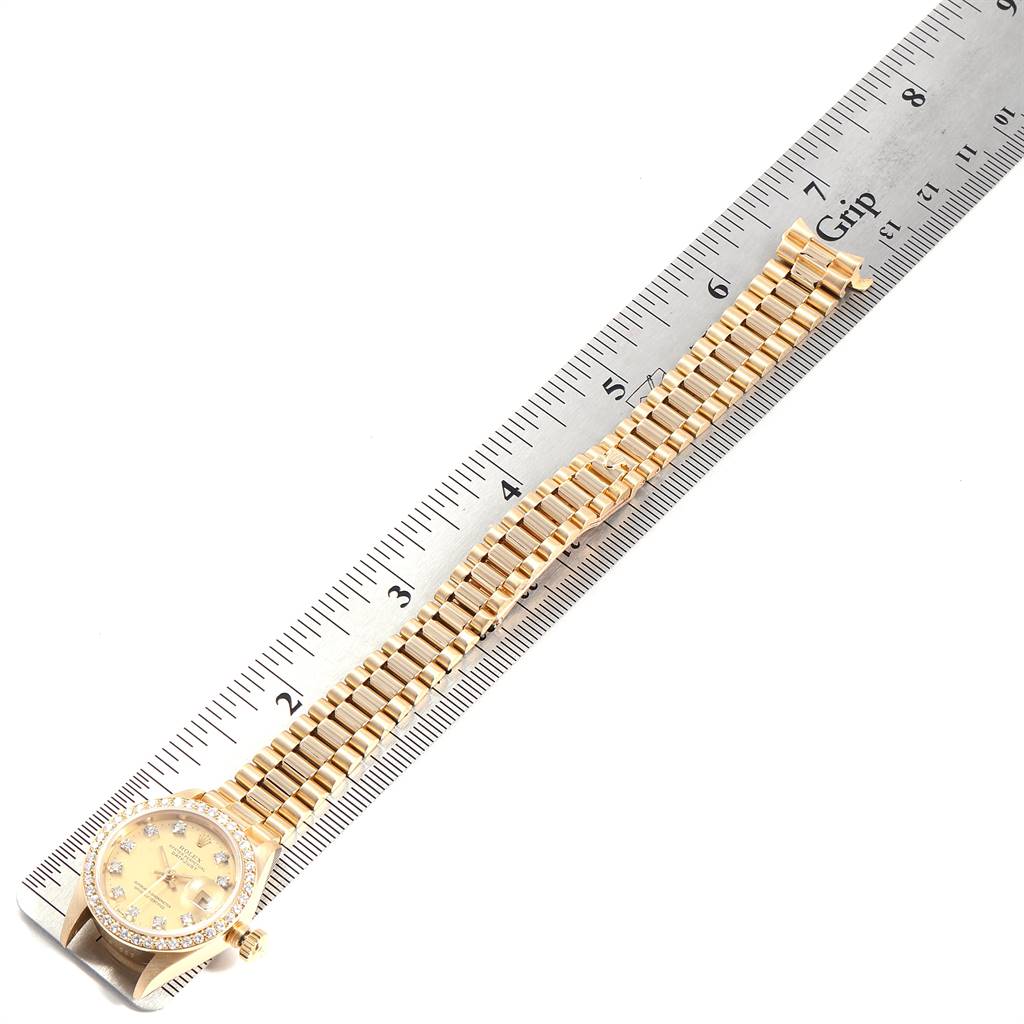 The image shows a President model Rolex watch with its band laid flat beside a ruler for scale.