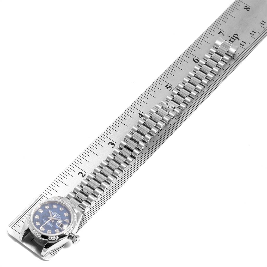 The image shows a top-down view of a Rolex President 179369 Women's White Gold Blue Dial 179369 Women's White Gold Blue Dial model watch lying next to a ruler, emphasizing its band and face.