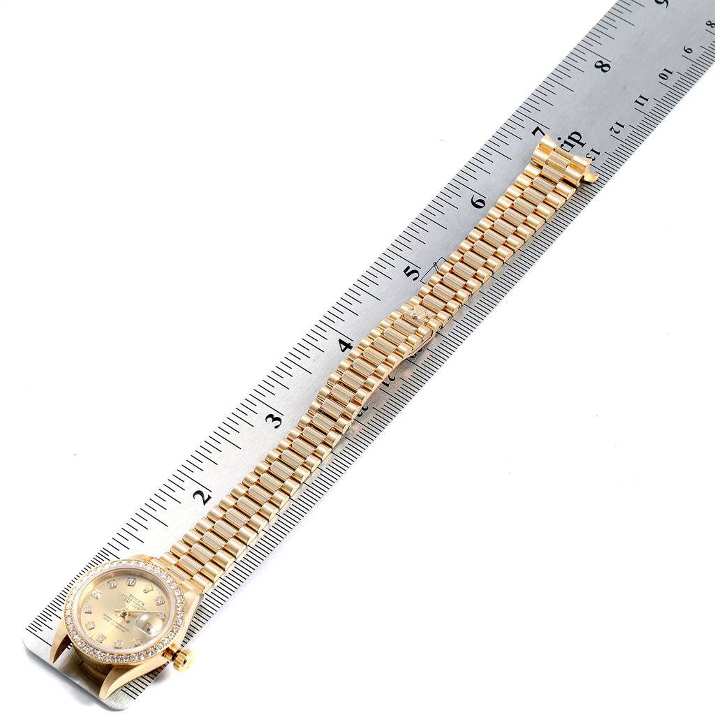 This image shows a Rolex President 69138 Women
s Yellow Gold Champagne Dial 69138 Women
s Yellow Gold Champagne Dial model watch laid flat next to a ruler, displaying the watch face, bezel, and entire bracelet.