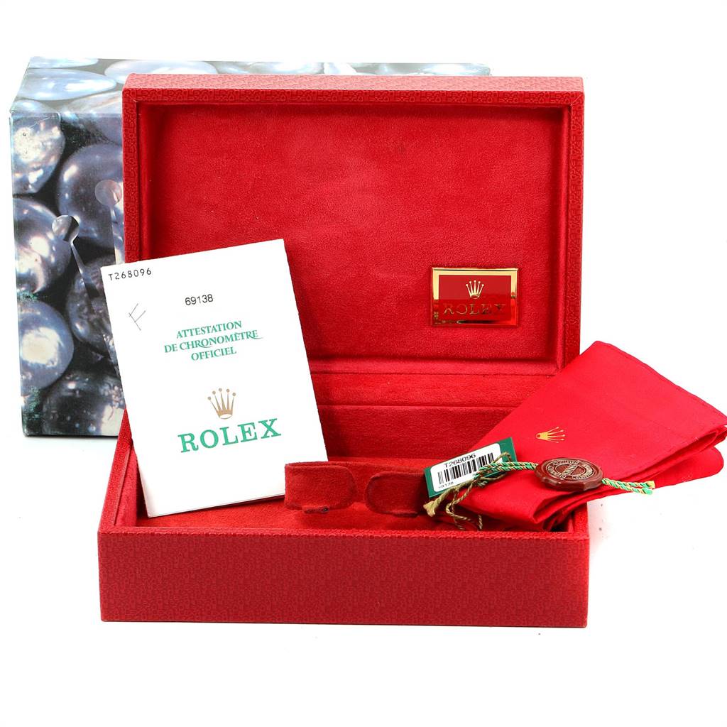 The image shows accessories for a Rolex President 69138 Women
s Yellow Gold Champagne Dial 69138 Women
s Yellow Gold Champagne Dial model watch, including a red box, a document, and a red pouch.