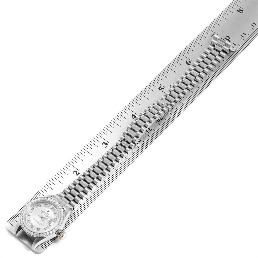 The image shows a Rolex President 69179 Women's White Gold Silver Dial 69179 Women's White Gold Silver Dial model watch, featuring its face and bracelet band laid out against a ruler.