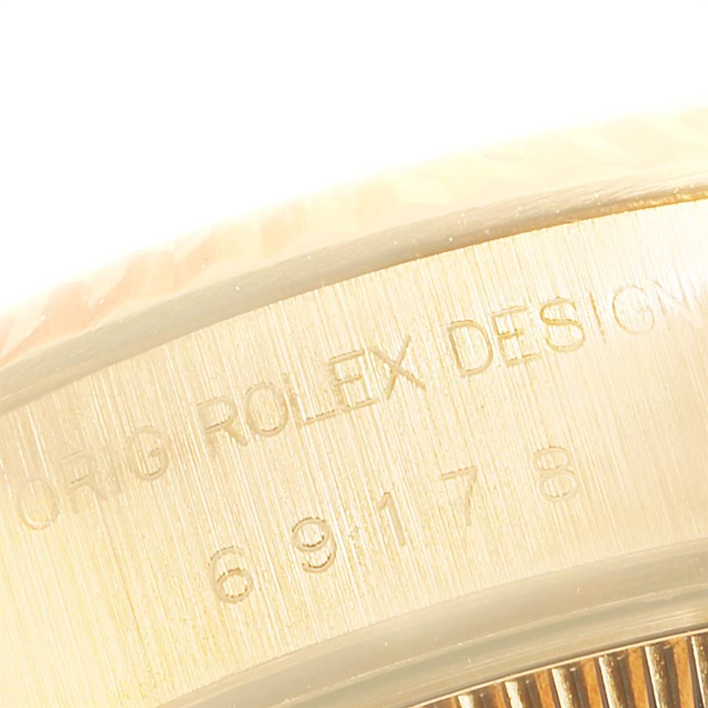 This image shows a close-up of the edge of a Rolex President 69178 Women's Yellow Gold White Dial 69178 Women's Yellow Gold White Dial model watch case with engraved text.