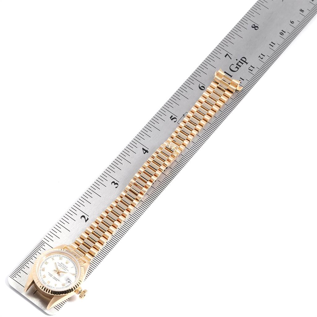 The image shows a Rolex President 69178 Women's Yellow Gold White Dial 69178 Women's Yellow Gold White Dial model watch laid flat alongside a ruler, highlighting the watch band and face.