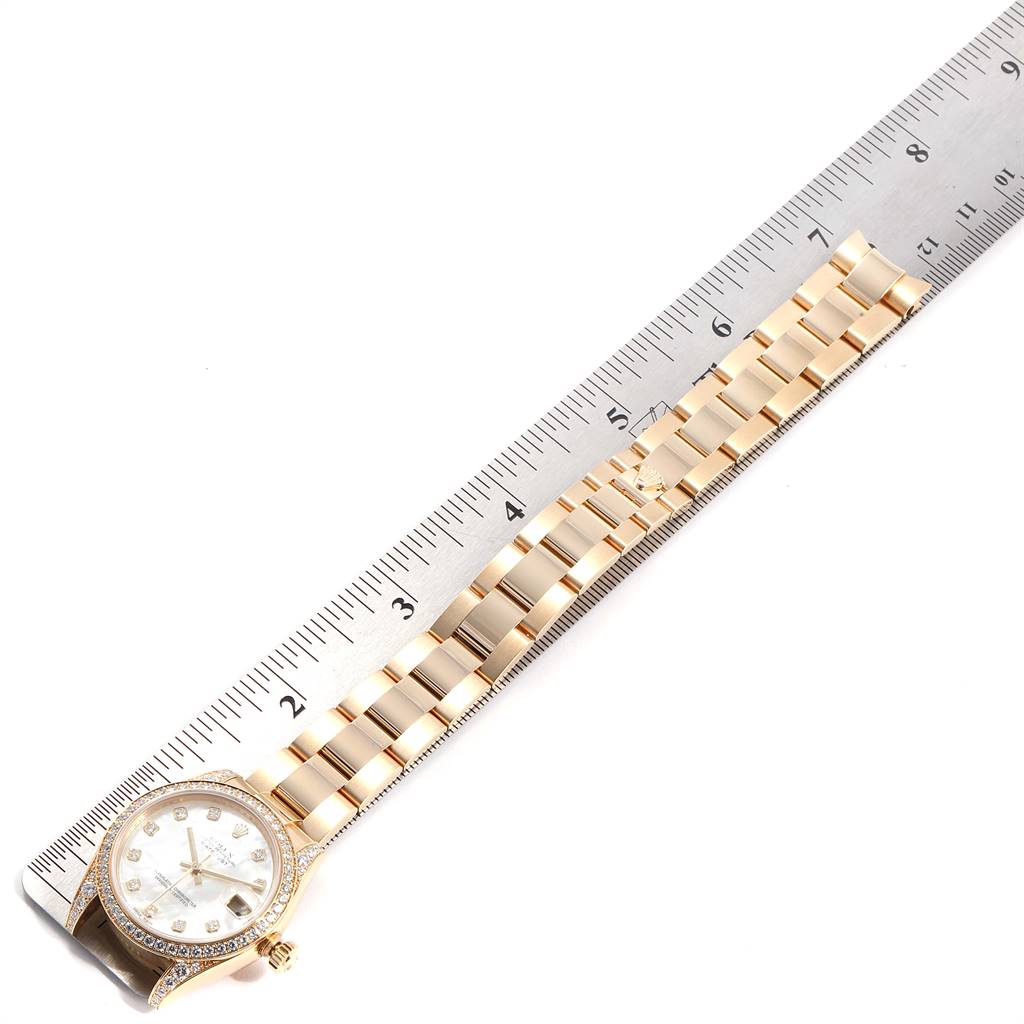 The Rolex President 178158 Women
s Yellow Gold Mother of Pearl Dial 178158 Women
s Yellow Gold Mother of Pearl Dial model watch is shown from a top-down angle with its band and face alongside a ruler.