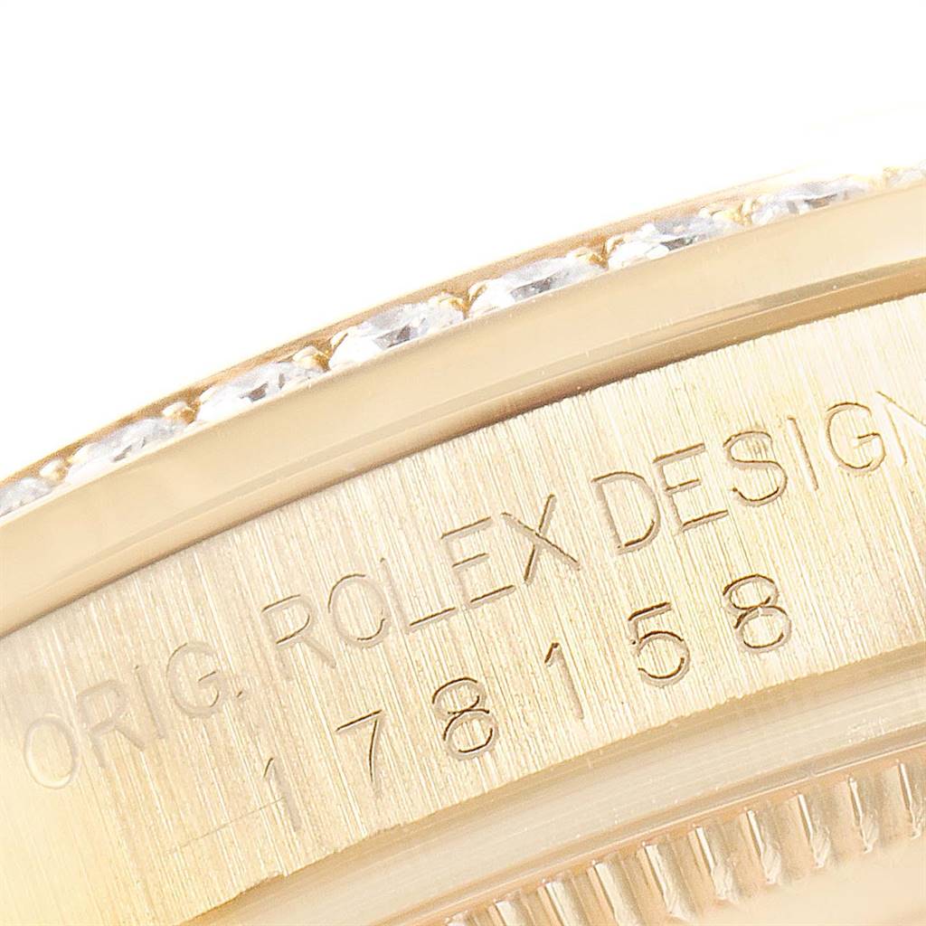 This close-up image of the Rolex President 178158 Women
s Yellow Gold Mother of Pearl Dial 178158 Women
s Yellow Gold Mother of Pearl Dial model shows part of the bezel with diamonds and the case with engraved text.