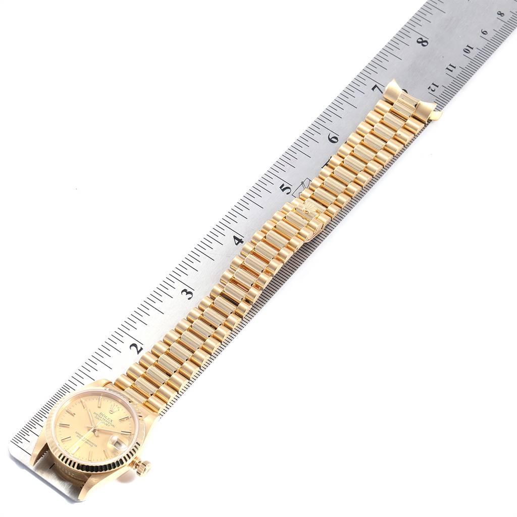 The image shows a Rolex President 68278 Women
s Yellow Gold Champagne Dial 68278 Women
s Yellow Gold Champagne Dial model watch photographed from a top-down angle with its band and face visible next to a ruler.