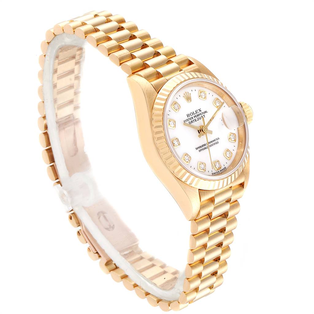 The image shows a Rolex President 69138 Women
s Yellow Gold White Dial 69138 Women
s Yellow Gold White Dial model watch at a slight angle, displaying its gold band, case, and diamond-encrusted white dial.