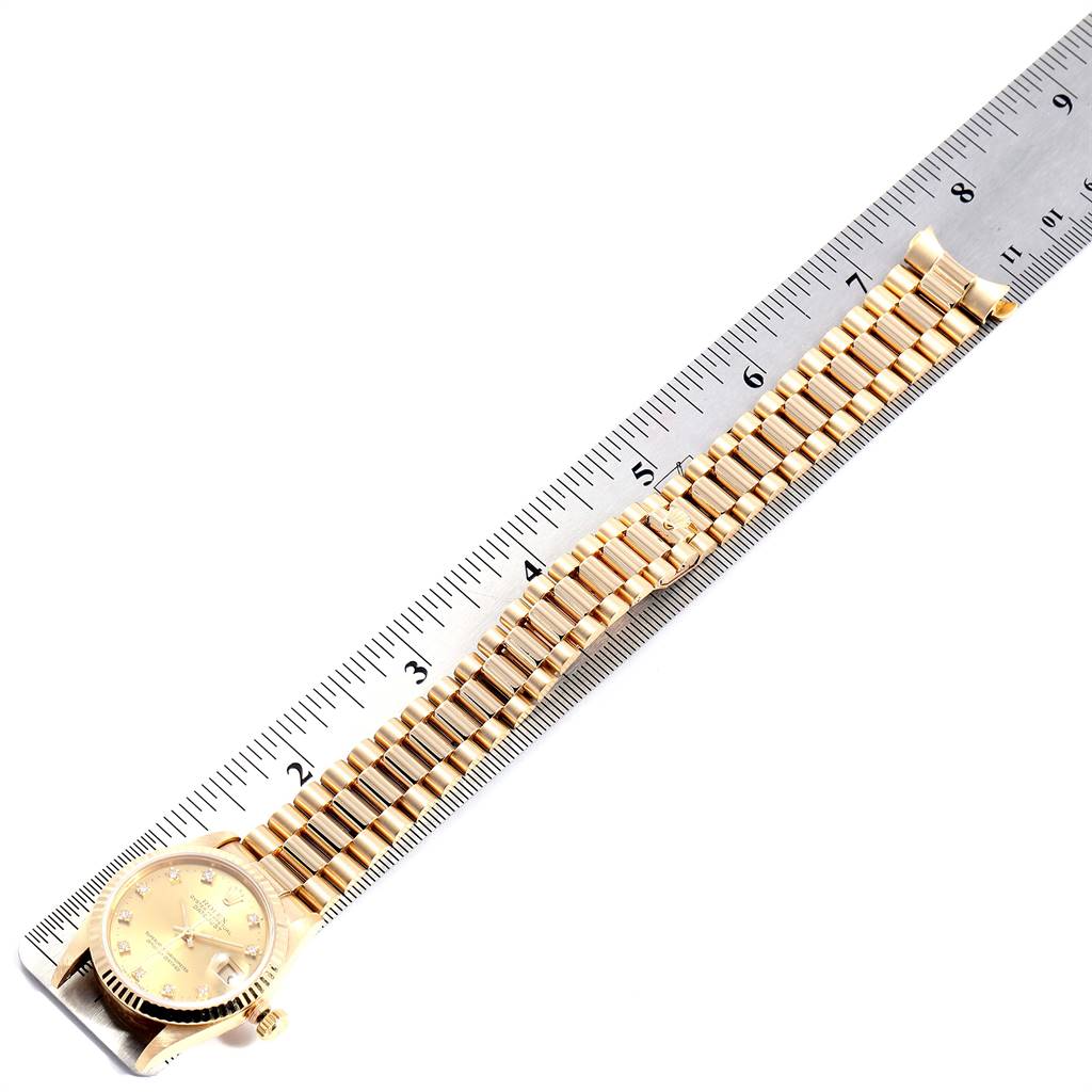 The image shows a Rolex President 68278 Women
s Yellow Gold Champagne Dial 68278 Women
s Yellow Gold Champagne Dial model watch laid flat alongside a ruler, capturing both the face and the full length of the bracelet.