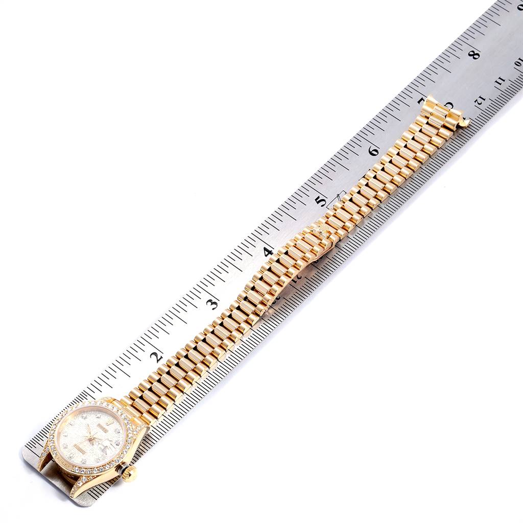 The image shows a top view of a Rolex President 69158 Women's Yellow Gold Silver Dial 69158 Women's Yellow Gold Silver Dial model watch, featuring its face and gold bracelet, placed next to a ruler for measurement.