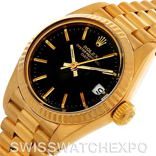 The image shows a Rolex President 6917 Women's Yellow Gold Black Dial 6917 Women's Yellow Gold Black Dial model watch angled to display the black dial, gold case, fluted bezel, and a portion of the bracelet.