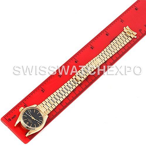 The Rolex President 6917 Women's Yellow Gold Black Dial 6917 Women's Yellow Gold Black Dial model watch is displayed from a top-down angle alongside a red ruler for measurement.
