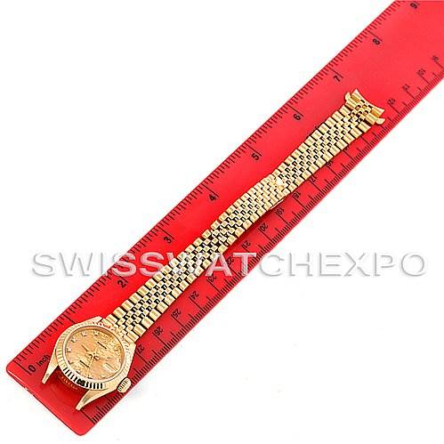This image shows a full view of a Rolex President 69178 Women's Yellow Gold Champagne Dial 69178 Women's Yellow Gold Champagne Dial watch, including its face, bezel, and bracelet, laid next to a red ruler.