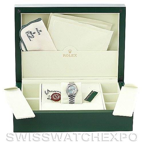 This image shows a green Rolex watch box containing a Rolex watch, additional accessories, tags, and a cleaning cloth.