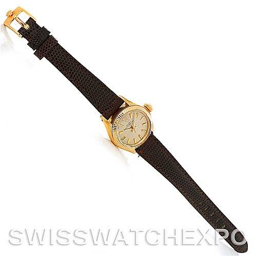 The image shows a Rolex President 6719 Women
s Yellow Gold Champagne Dial 6719 Women
s Yellow Gold Champagne Dial model watch at an angled top-down view, highlighting its brown leather strap and gold case.