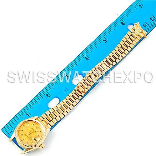 The image shows a Rolex President 6917 Women's Yellow Gold Champagne Dial 6917 Women's Yellow Gold Champagne Dial model watch laying flat next to a ruler, showcasing its golden bracelet and face from a top-down angle.