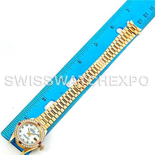 The image shows a Rolex President 69068 Women
s Yellow Gold Mother of Pearl Dial 69068 Women
s Yellow Gold Mother of Pearl Dial model watch laid flat, highlighting the face, bezel, and bracelet next to a blue ruler for scale.