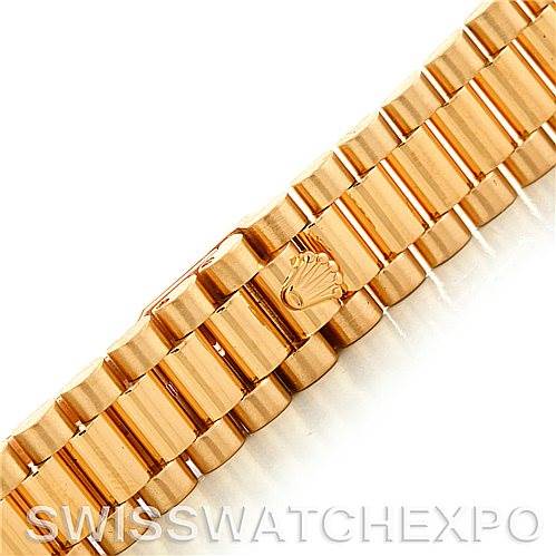 The image shows a close-up of the gold President bracelet of a Rolex watch, featuring the crown logo on the clasp.