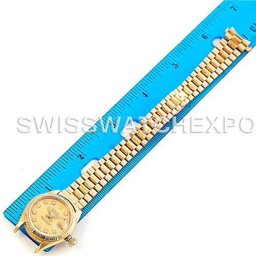 The Rolex President 69278 Women's Yellow Gold Champagne Dial 69278 Women's Yellow Gold Champagne Dial model watch is displayed fully extended next to a blue ruler, showing the dial and bracelet band.