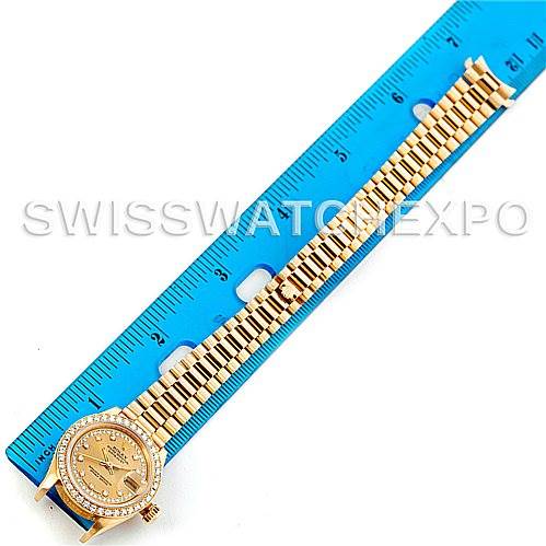 The image shows a Rolex President 69138 Women's Yellow Gold Champagne Dial 69138 Women's Yellow Gold Champagne Dial model watch from a top-down angle, displaying its gold bracelet and diamond-studded bezel beside a ruler.