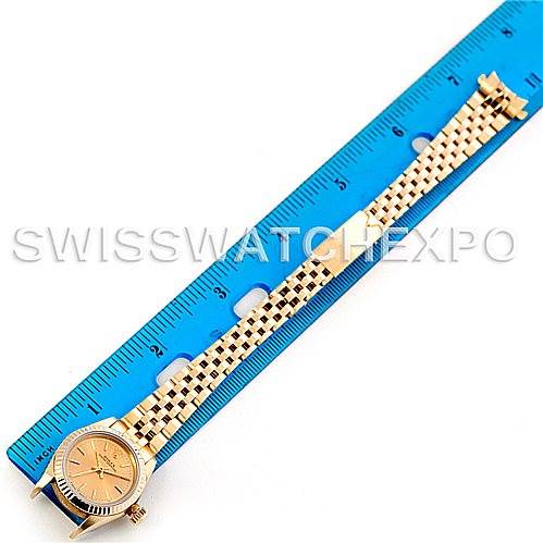 The Rolex President 67197 Women's Yellow Gold Champagne Dial 67197 Women's Yellow Gold Champagne Dial watch is shown from above, displaying the face, dial, and its gold bracelet fully extended against a blue ruler.