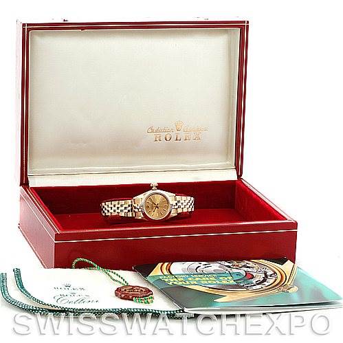 This image shows a Rolex President 67197 Women's Yellow Gold Champagne Dial 67197 Women's Yellow Gold Champagne Dial model watch in an open red case with accompanying documentation and accessories.