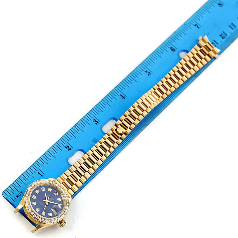 The Rolex President 69138 Women's Yellow Gold Blue Dial 69138 Women's Yellow Gold Blue Dial model watch is shown from the front, with the face and gold band next to a blue ruler for scale.