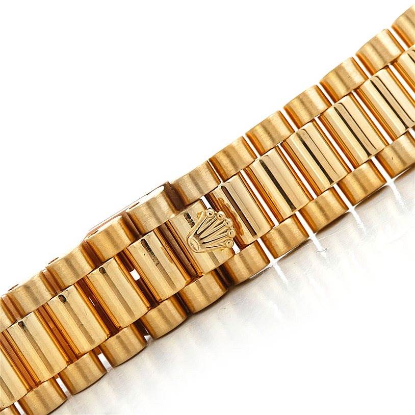 The image shows a close-up of the gold bracelet of a Rolex President 69138 Women's Yellow Gold Blue Dial 69138 Women's Yellow Gold Blue Dial model watch, featuring the signature crown logo.