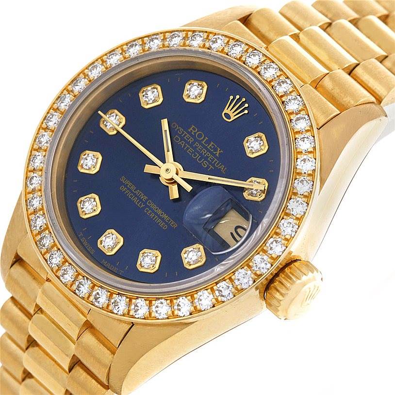 The image shows a close-up view of a Rolex President 69138 Women's Yellow Gold Blue Dial 69138 Women's Yellow Gold Blue Dial model, highlighting its diamond bezel, blue dial, and gold bracelet.