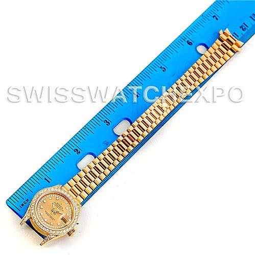 This image shows a top-down view of a Rolex President 69158 Women's Yellow Gold Champagne Dial 69158 Women's Yellow Gold Champagne Dial model watch alongside a blue ruler for scale.