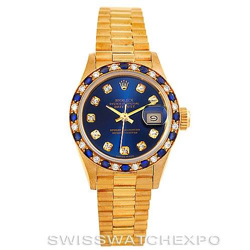 The image shows a frontal view of a Rolex President 69198 Women's Yellow Gold Blue Dial 69198 Women's Yellow Gold Blue Dial model watch, displaying its gold bracelet, blue dial with diamond markers, and date window.