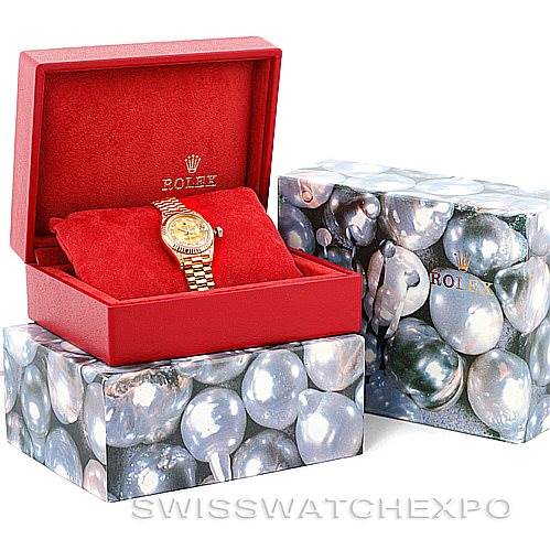 This image shows a Rolex President 69238 Women's Yellow Gold Champagne Dial 69238 Women's Yellow Gold Champagne Dial model watch in a red display box, placed on decorative packaging boxes.