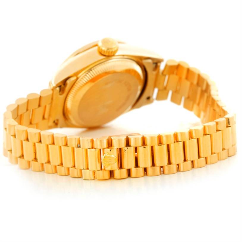 The image shows the back and bracelet of a Rolex President 69158 Women's Yellow Gold Black Dial 69158 Women's Yellow Gold Black Dial model watch at a low angle.