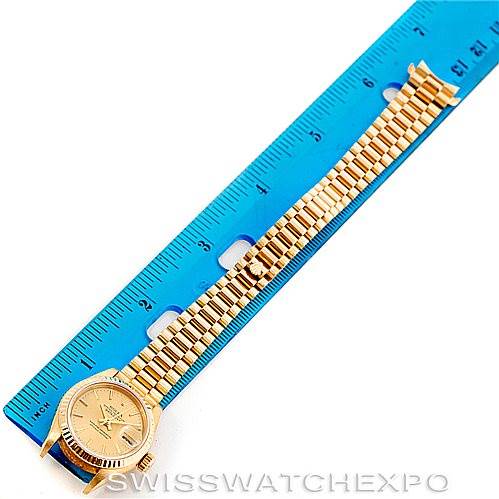 The image shows a Rolex President 69178 Women's Yellow Gold Champagne Dial 69178 Women's Yellow Gold Champagne Dial model watch placed next to a blue ruler for scale, displaying the watch face and full bracelet.