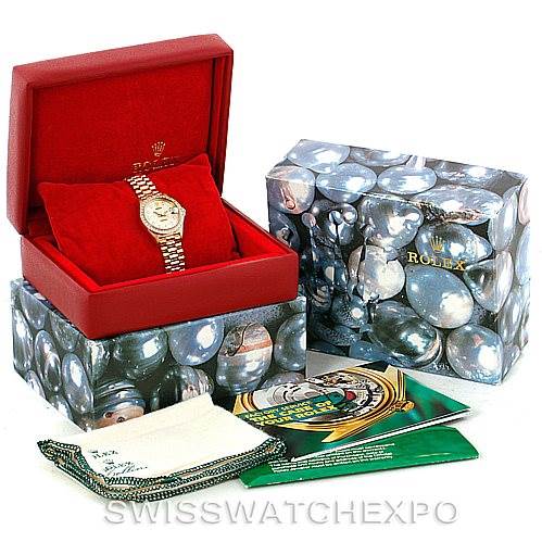 This image shows a Rolex President 69138 Women
s Yellow Gold Beige Dial 69138 Women
s Yellow Gold Beige Dial model watch in its red box along with its outer packaging, booklets, and cleaning cloth.