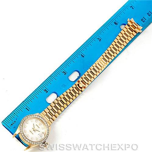 The image shows a Rolex President 69138 Women
s Yellow Gold Beige Dial 69138 Women
s Yellow Gold Beige Dial model watch lying flat, highlighting its dial, bezel, and bracelet, with a ruler for scale.