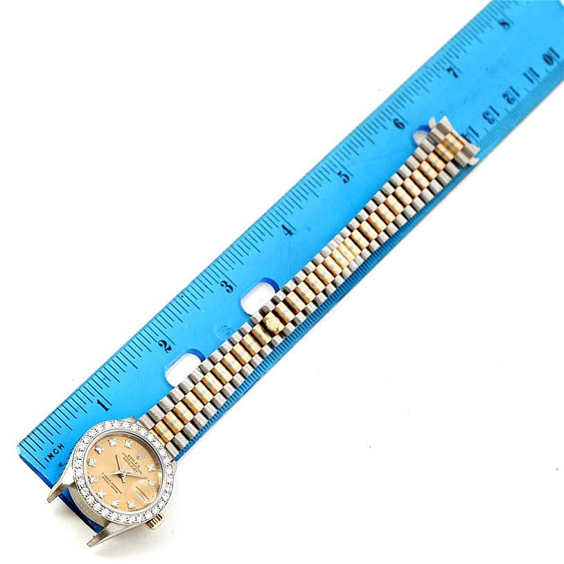 The Rolex President 69179B Women's White Gold Brown Dial 69179B Women's White Gold Brown Dial model watch is shown from an overhead angle, including the face, bezel, and part of the bracelet alongside a ruler.