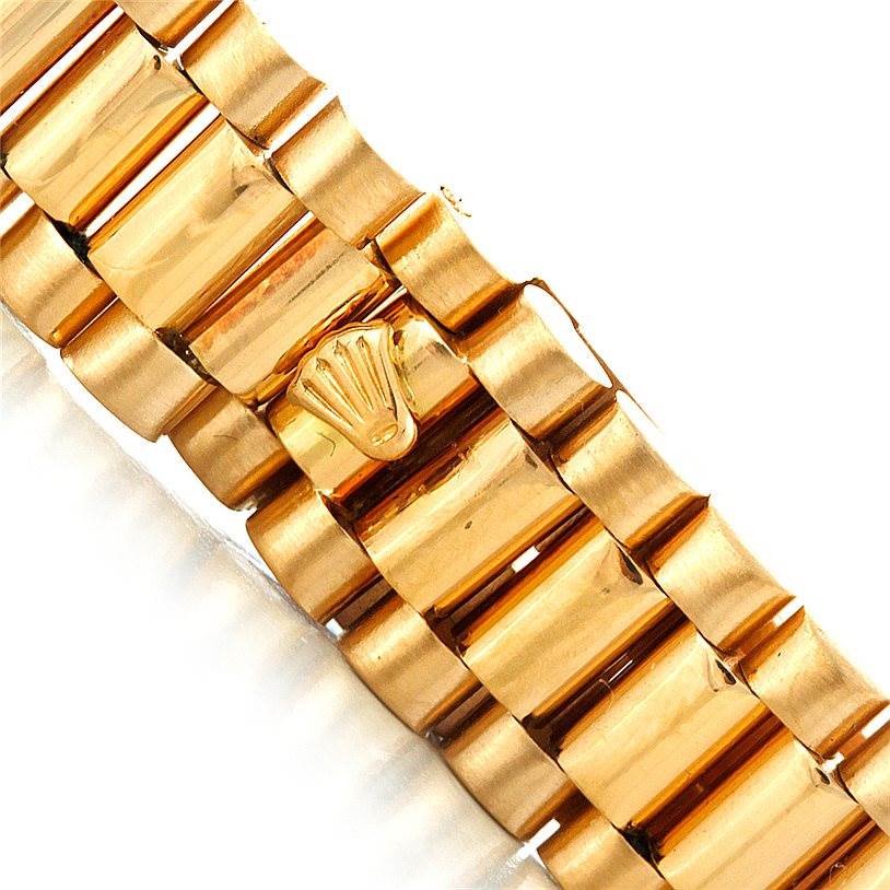 The image shows a close-up of the gold bracelet and clasp with the Rolex logo on the President model by Rolex.