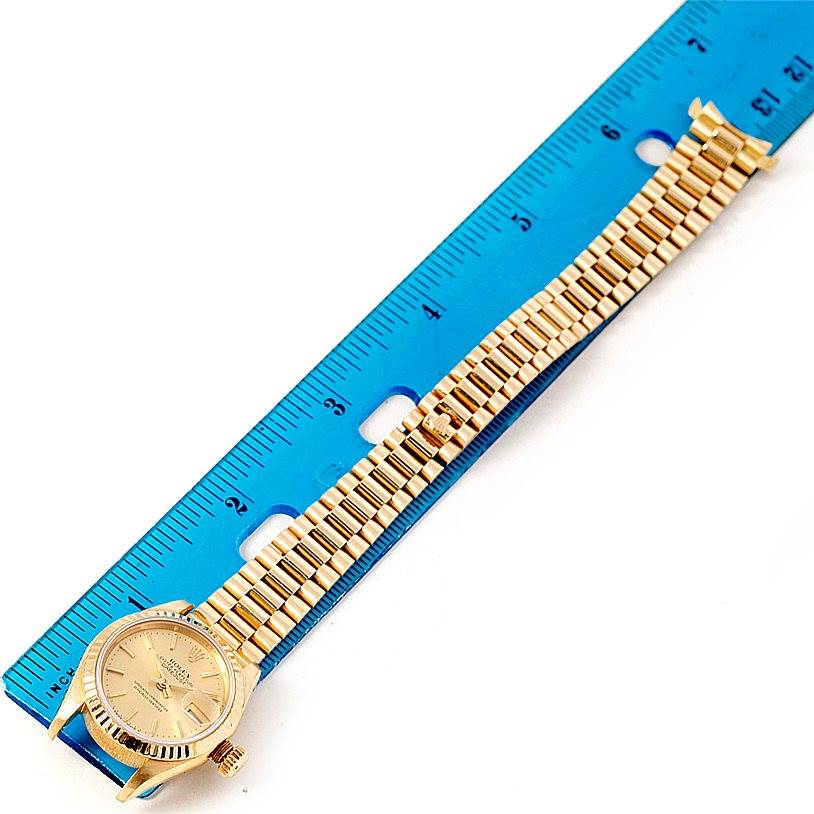 The image shows a Rolex President 69178 Women's Yellow Gold Champagne Dial 69178 Women's Yellow Gold Champagne Dial model watch laid flat against a blue ruler, displaying the watch face and bracelet.