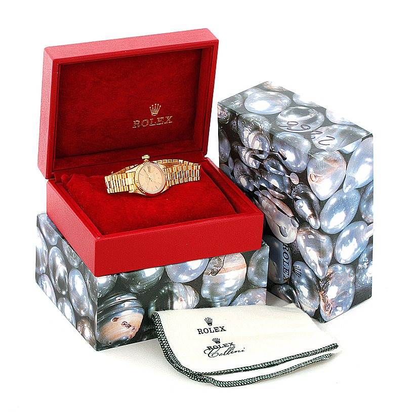 The Rolex President 69178 Women's Yellow Gold Champagne Dial 69178 Women's Yellow Gold Champagne Dial watch is shown front-facing in an open red box, with packaging and a cleaning cloth nearby.