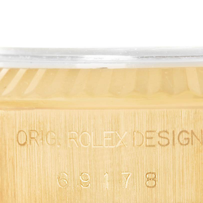 This close-up shows part of the bezel and the engraved side of a Rolex President 69178 Women's Yellow Gold Beige Dial 69178 Women's Yellow Gold Beige Dial model watch.