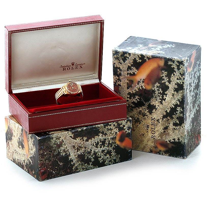 This image shows a Rolex President 6917 Women's Yellow Gold Brown Dial 6917 Women's Yellow Gold Brown Dial model watch inside an open red box with its outer decorative packaging also visible.