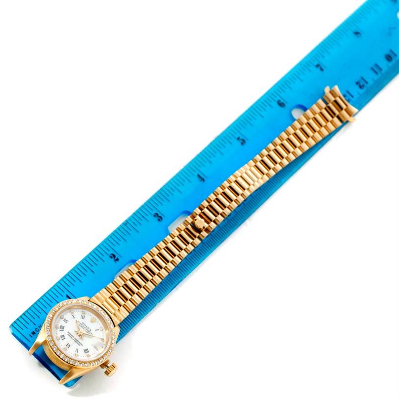 The Rolex President 69178 Women's Yellow Gold White Dial 69178 Women's Yellow Gold White Dial model watch is shown from a top-down angle, displaying the face, bezel, and fully extended bracelet, next to a ruler.