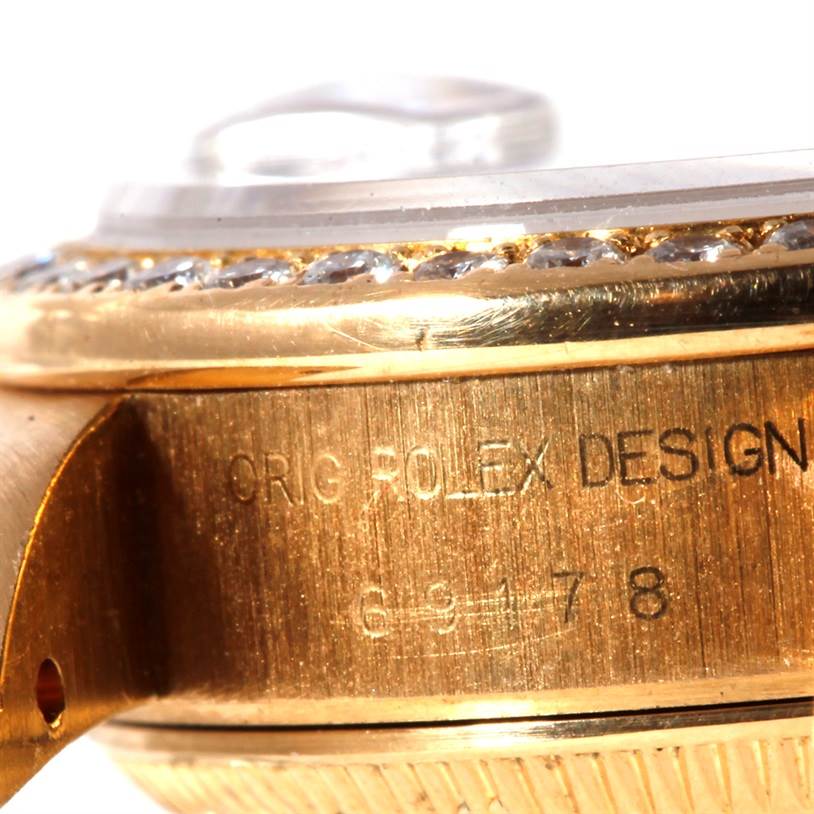This image shows a close-up of the side of a Rolex President 69178 Women's Yellow Gold White Dial 69178 Women's Yellow Gold White Dial model watch, highlighting the engraved design and part of the crystal and bezel.
