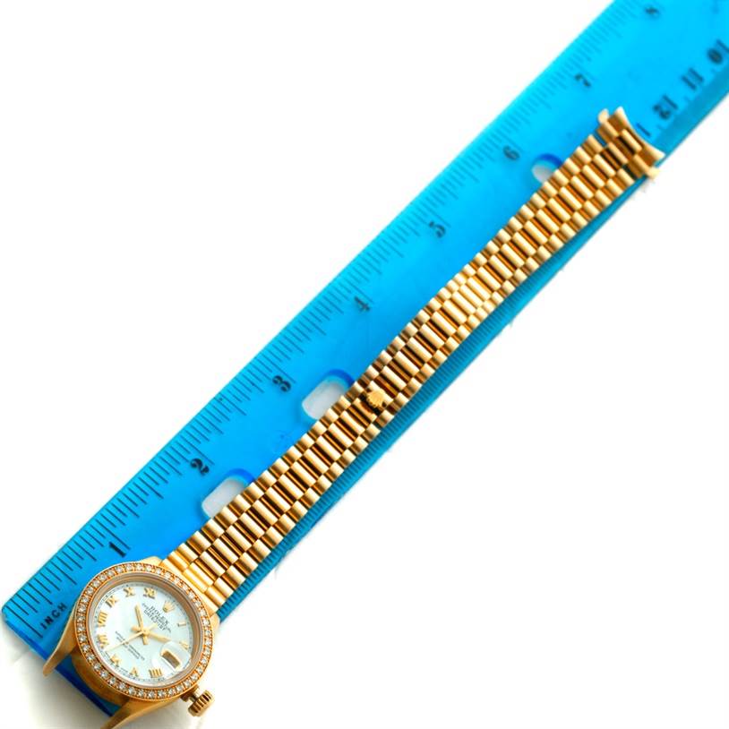 The image shows a Rolex President 69178 Women's Yellow Gold Mother of Pearl Dial 69178 Women's Yellow Gold Mother of Pearl Dial watch lying flat next to a blue ruler, displaying the watch face and bracelet.