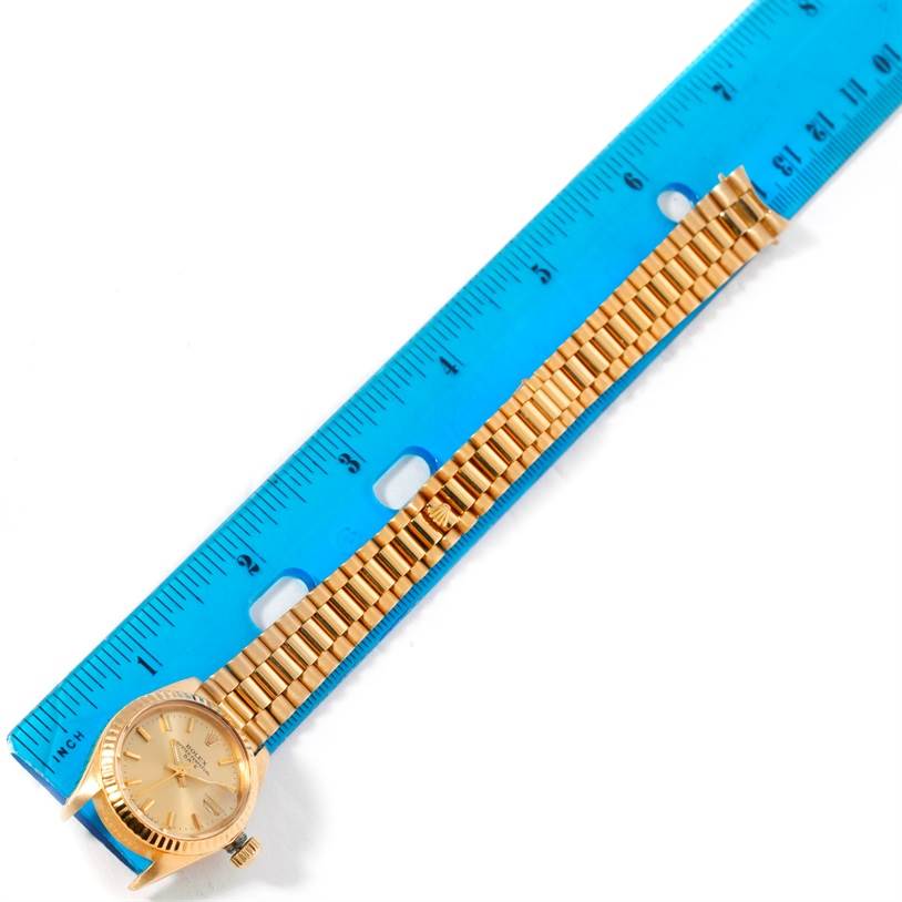 The image shows a Rolex President 6917 Women's Yellow Gold Champagne Dial 6917 Women's Yellow Gold Champagne Dial model watch positioned next to a blue ruler, displaying its face and bracelet.