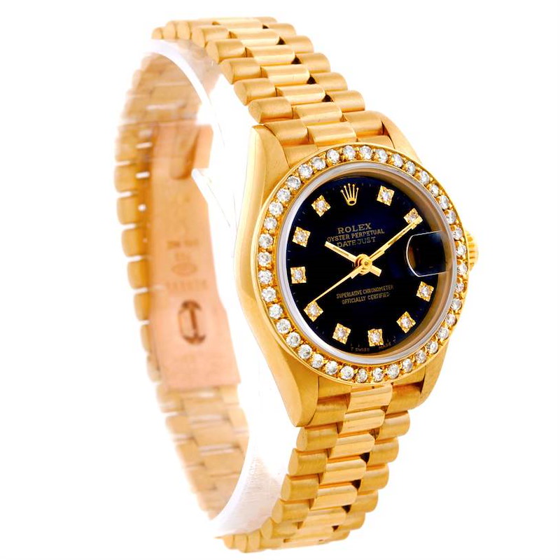 The image shows a Rolex President model watch at a slight angle, displaying its gold band, diamond-encrusted bezel, and black dial.