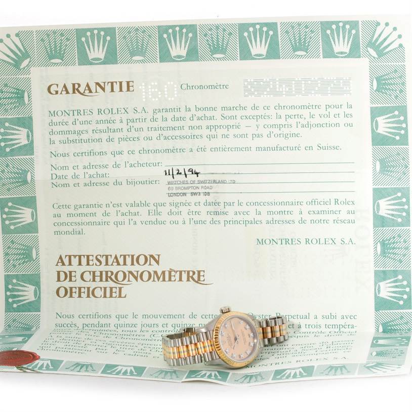 This image shows a Rolex President 69179B Women's White Gold Brown Dial 69179B Women's White Gold Brown Dial model watch placed on top of warranty and certification documents.