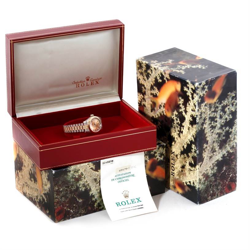 The image shows a Rolex President 69179B Women's White Gold Brown Dial 69179B Women's White Gold Brown Dial model watch positioned inside an open display box with its documentation alongside a decorative outer box.