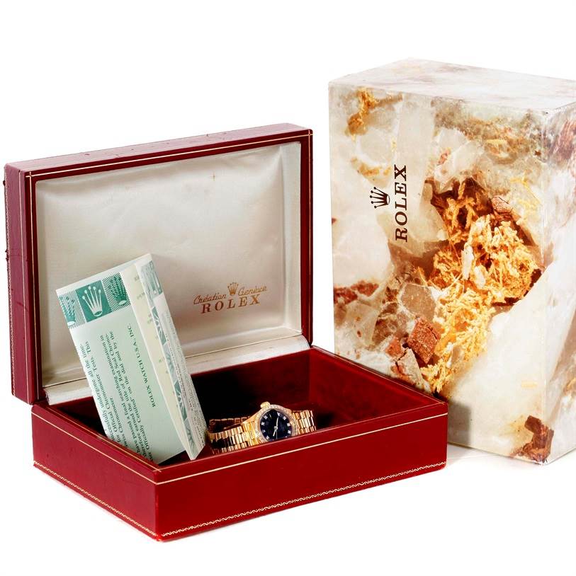 The watch and its accessories, including the box and warranty, are shown from a front angle in the image of the Rolex President 69178 Women's Yellow Gold Black Dial 69178 Women's Yellow Gold Black Dial model.