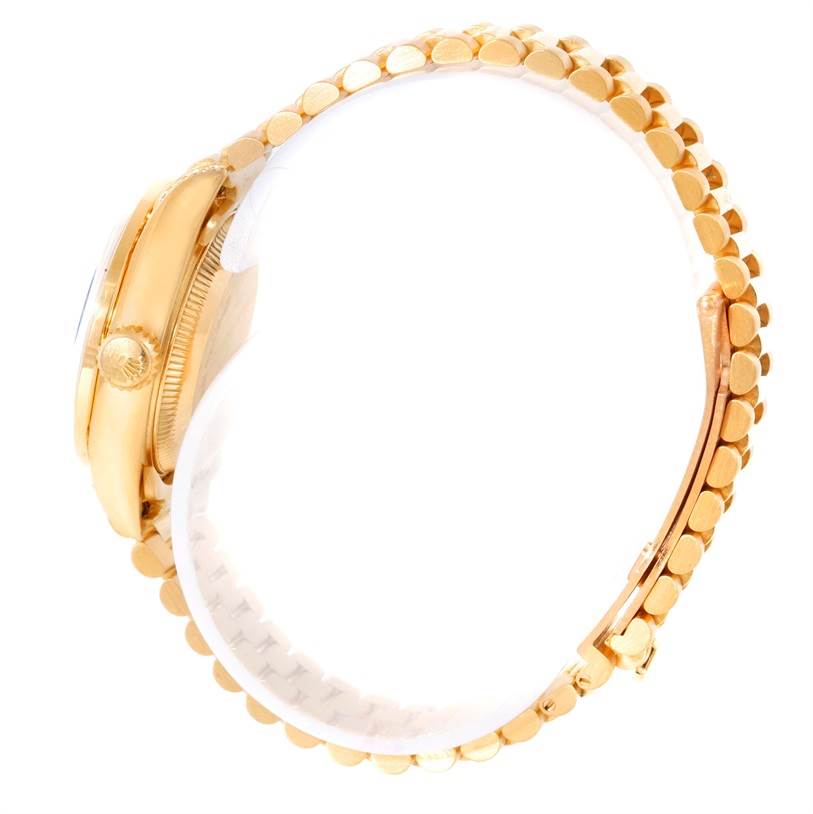 This side view of a Rolex President 69188 Women's Yellow Gold Blue Dial 69188 Women's Yellow Gold Blue Dial model watch shows the gold case, fluted crown, and a portion of the bracelet.